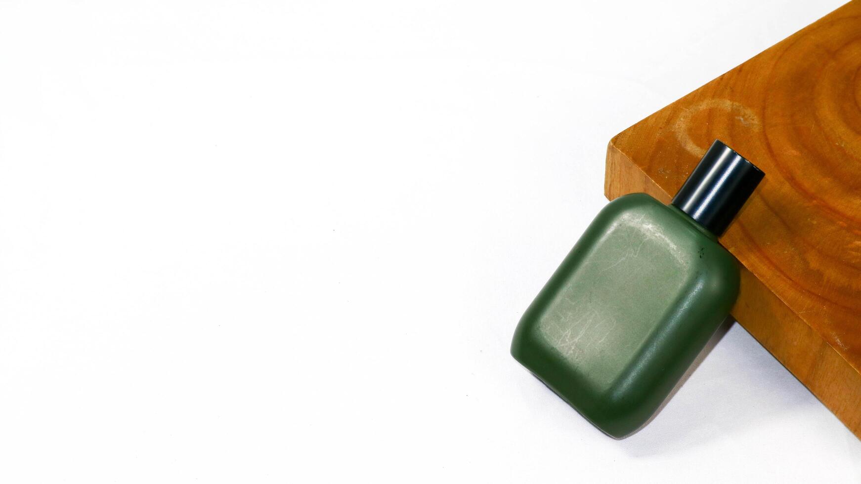 a green bottle of perfume sitting on top of a wooden block photo