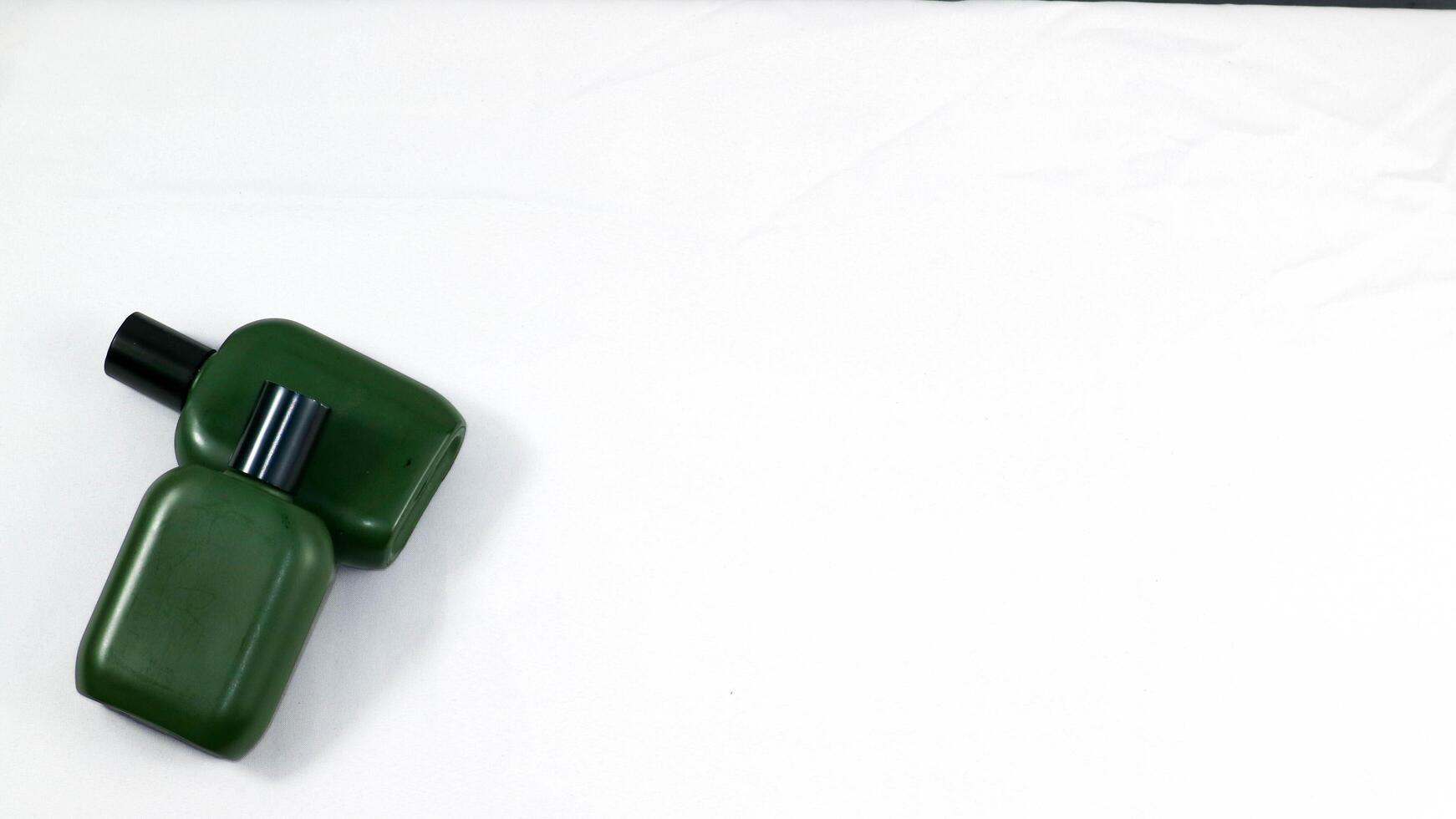 a green bottle and a black bottle sitting on a white surface photo
