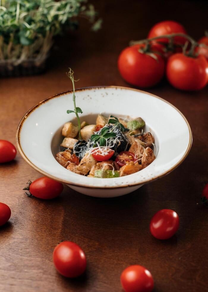 A bowl of food with tomatoes and cheese on a table photo