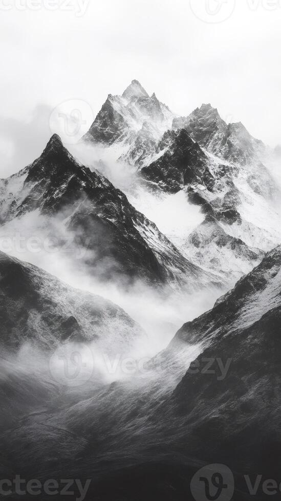 Majestic snow capped mountain peaks emerging from a sea of clouds in a black and white landscape photo