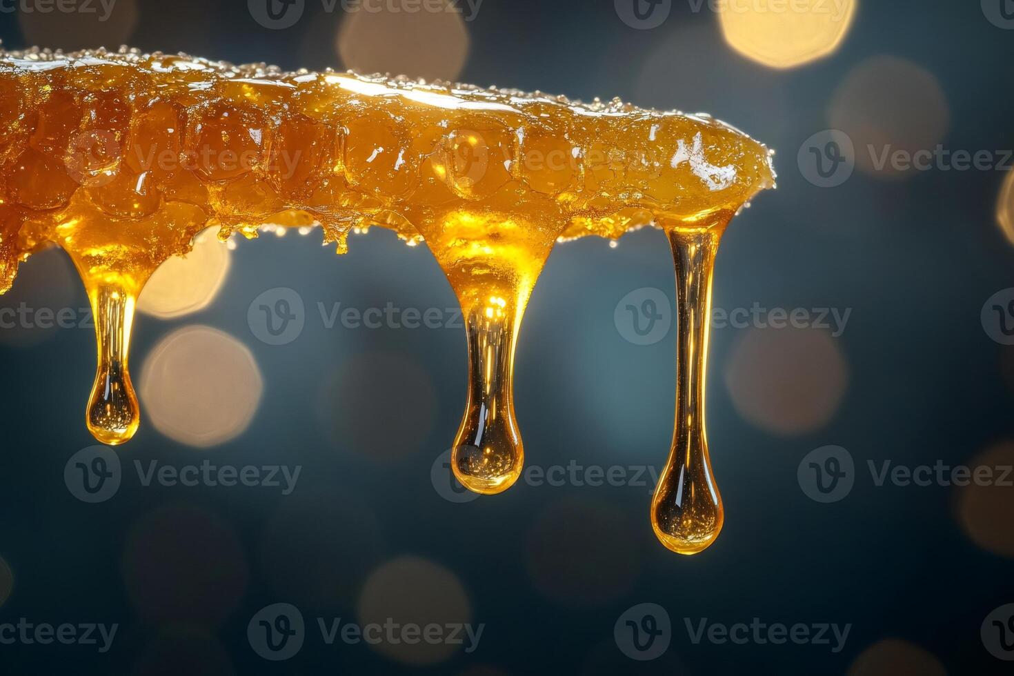 Honey dripping from honeycomb on dark background with golden bokeh photo