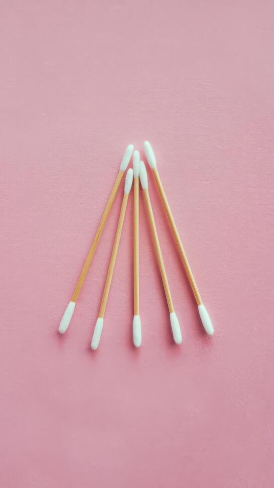 Three thin cotton swabs on pink background top view from above photo