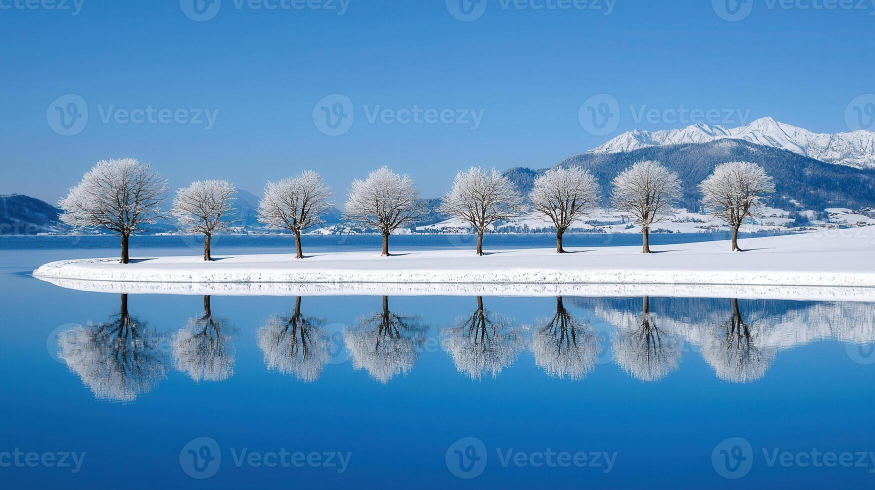 Serene Winter Landscape Snow Covered Trees Reflecting in a Calm Lake with Majestic Mountains in the Background photo
