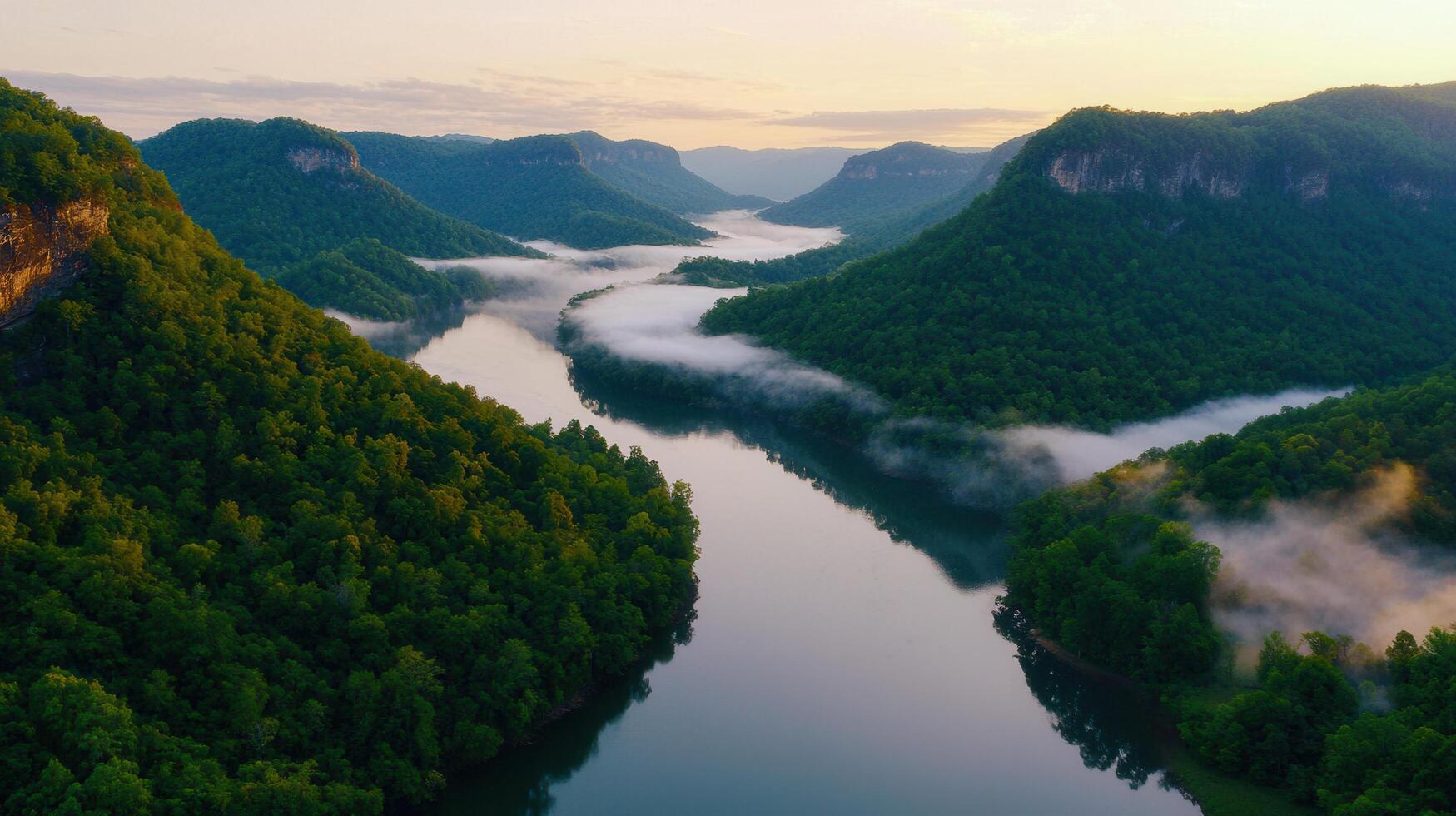 Serene Sunrise over Foggy River Winding Through Lush Green Mountains Scenic Landscape photo