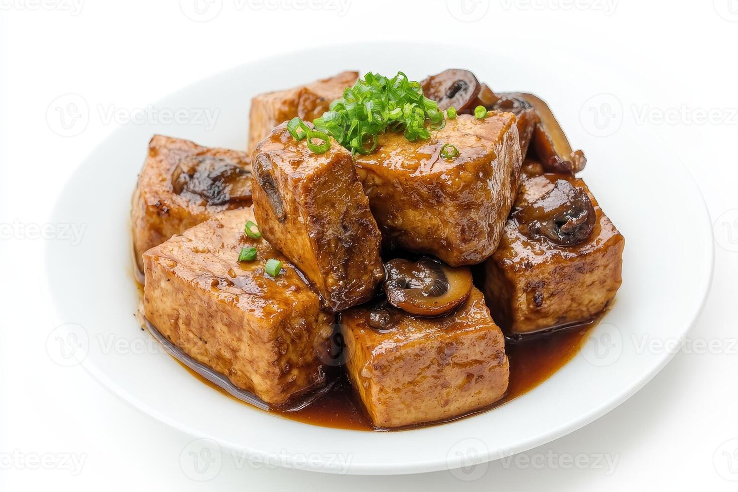A plate of tofu cubes in a savory sauce, garnished with green onions and mushrooms. photo