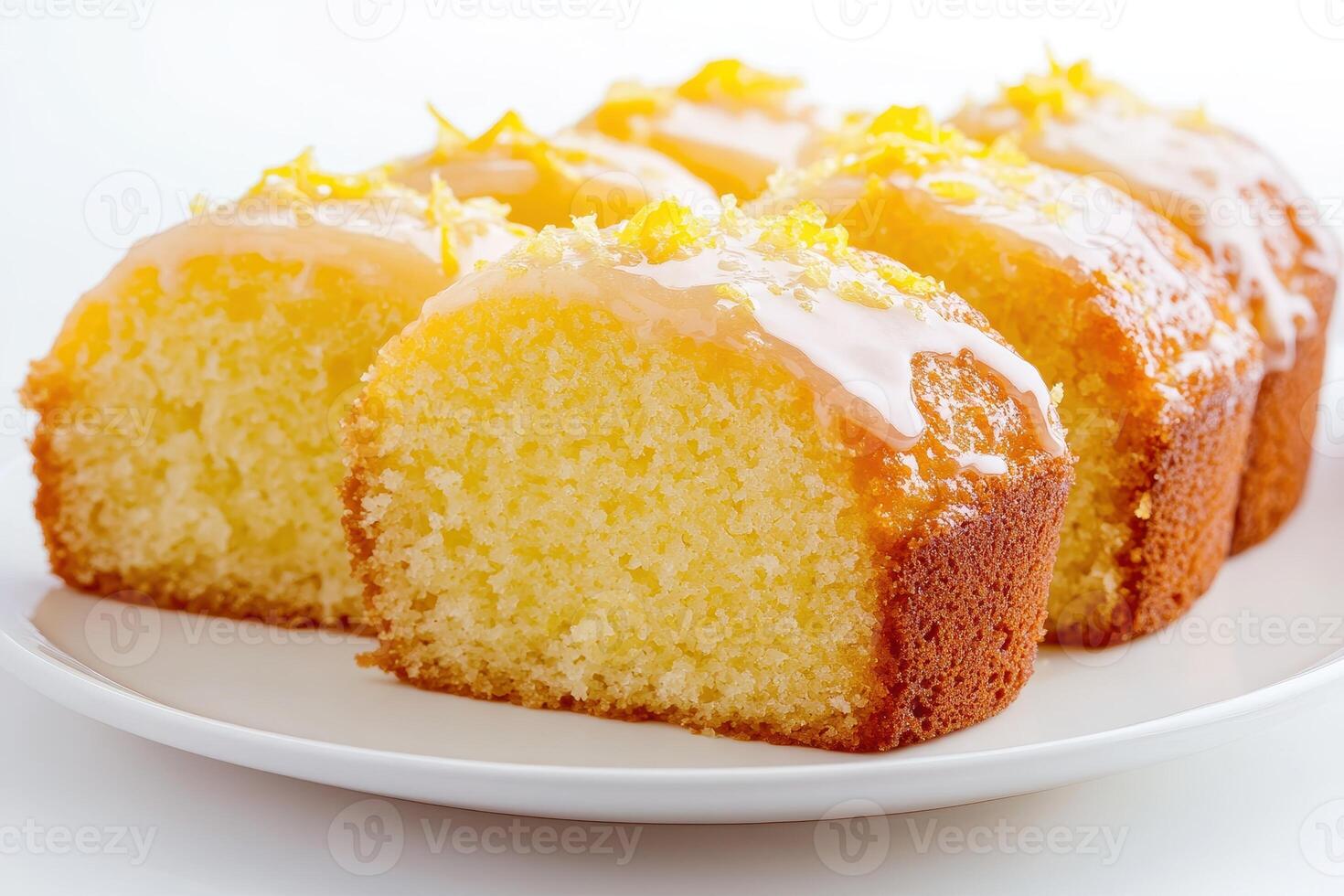 A close-up of sliced lemon cake with a glossy glaze and lemon zest on top photo