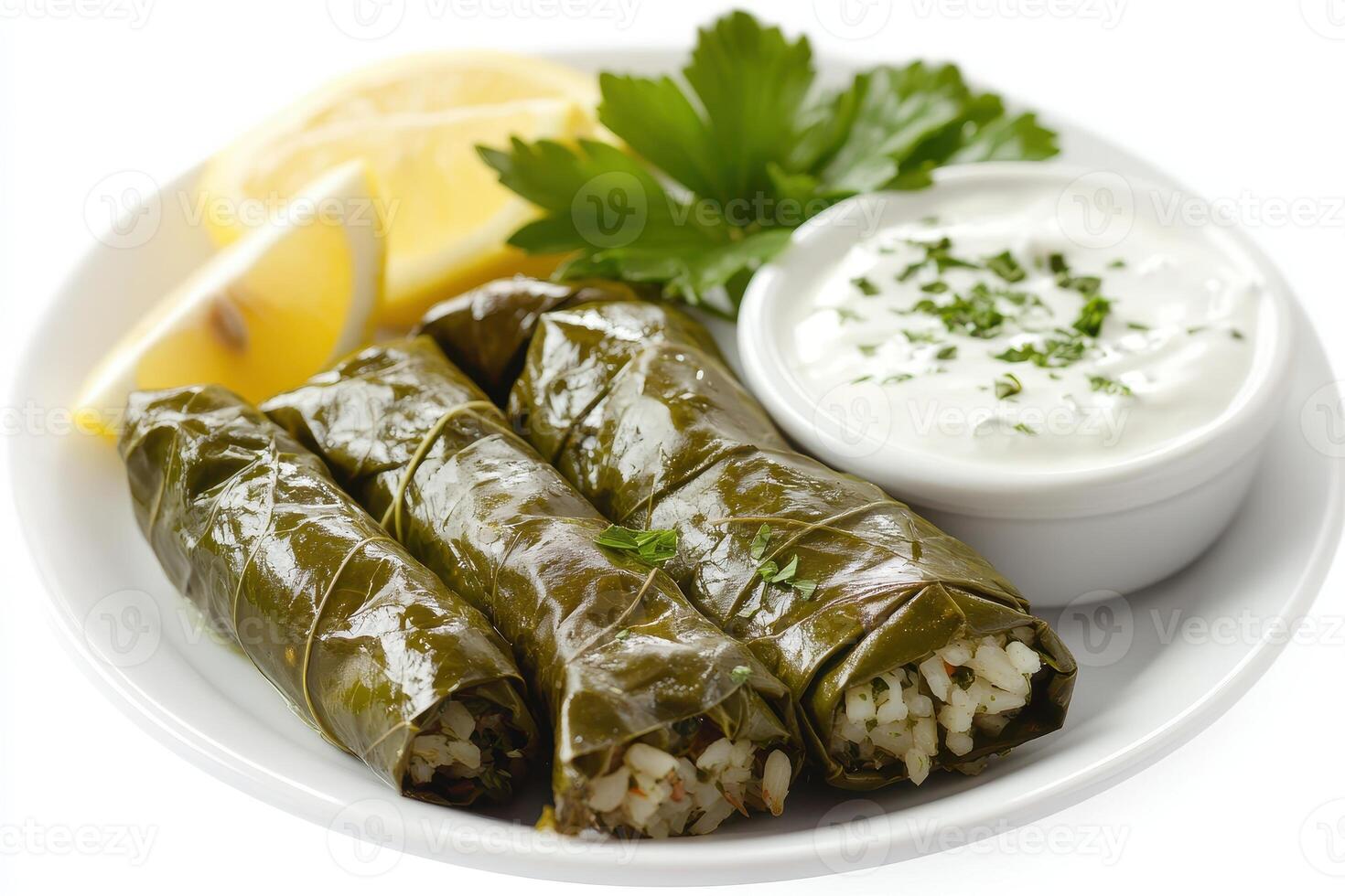 A plate of stuffed grape leaves served with lemon and yogurt sauce. photo