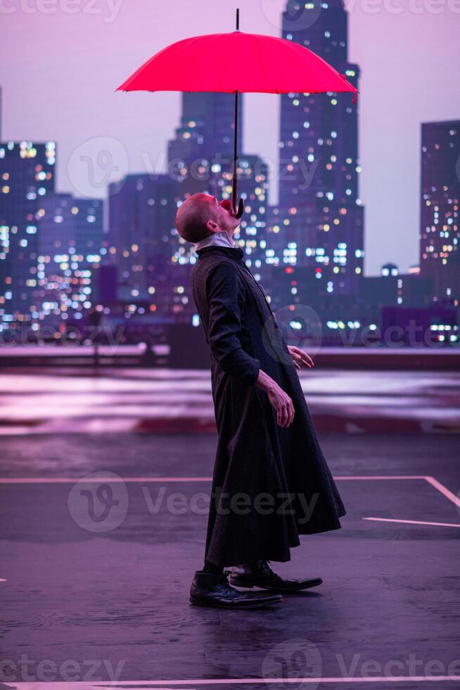 Mysterious Clown Performer with Red Umbrella in Urban Nightscape. photo