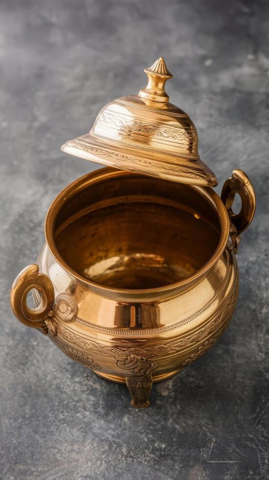 Urule or brass vesselan empty traditional south indian cooking vessel which is very shiny placed on grey textured background photo