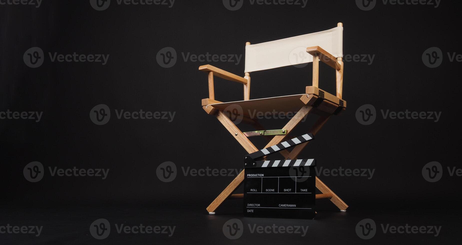 White director chair with clapper board on black background. photo