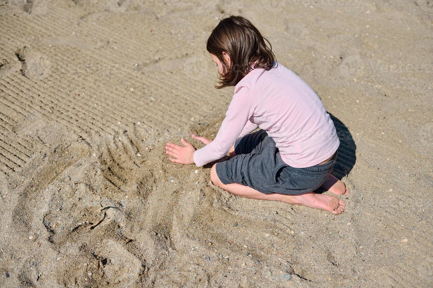 Young Child Enjoying Creative Sand Play on a Sunny Summer Day at the Beach photo