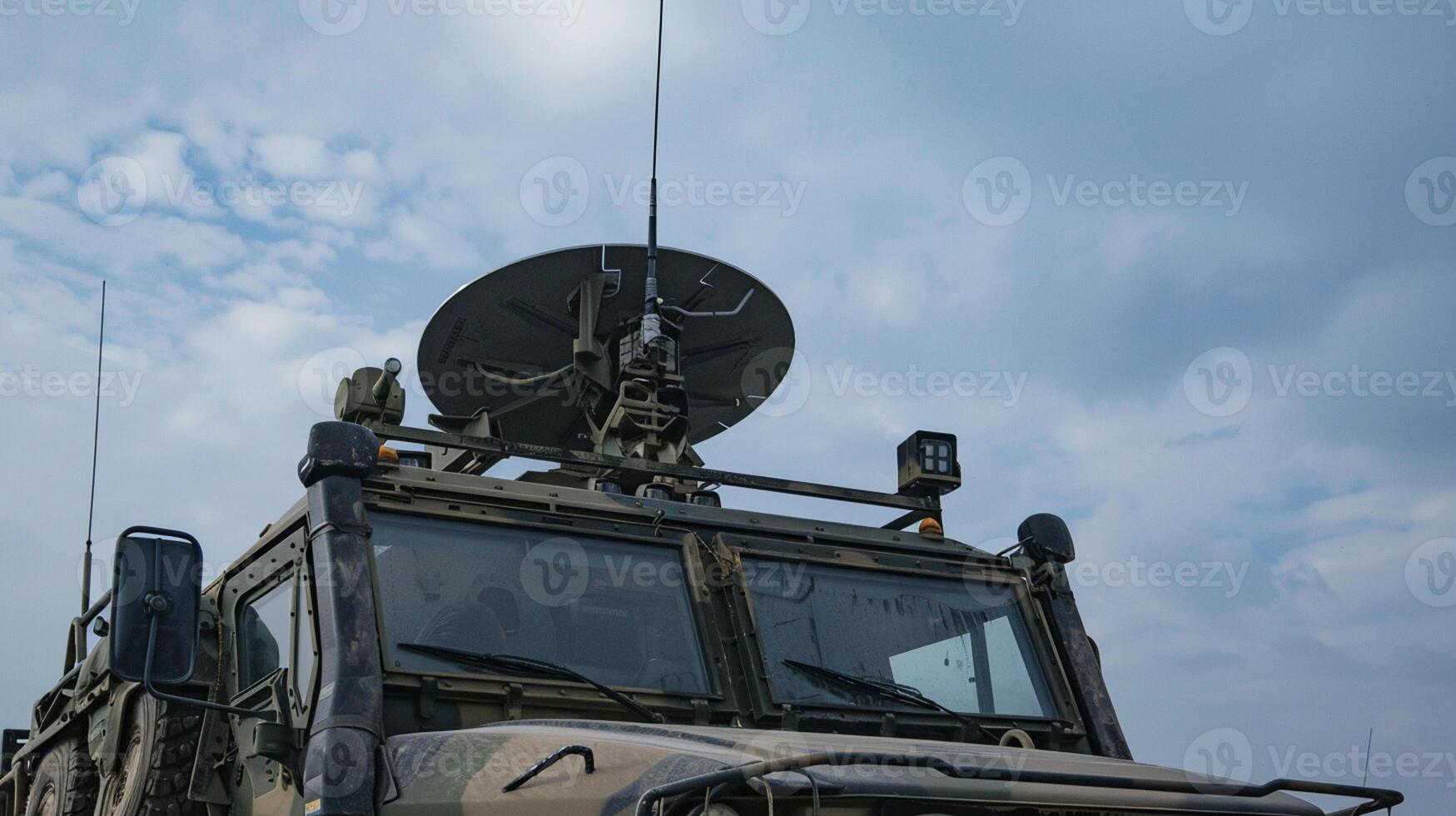 Military communication vehicle with a satellite dish antenna under a cloudy sky. photo