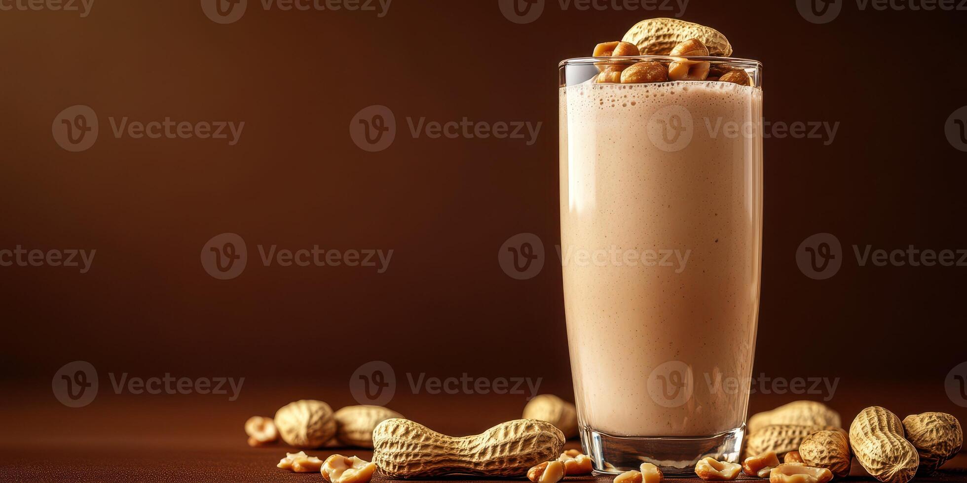 Creamy peanut butter smoothie garnished with whole peanuts in a glass on a dark wooden table photo