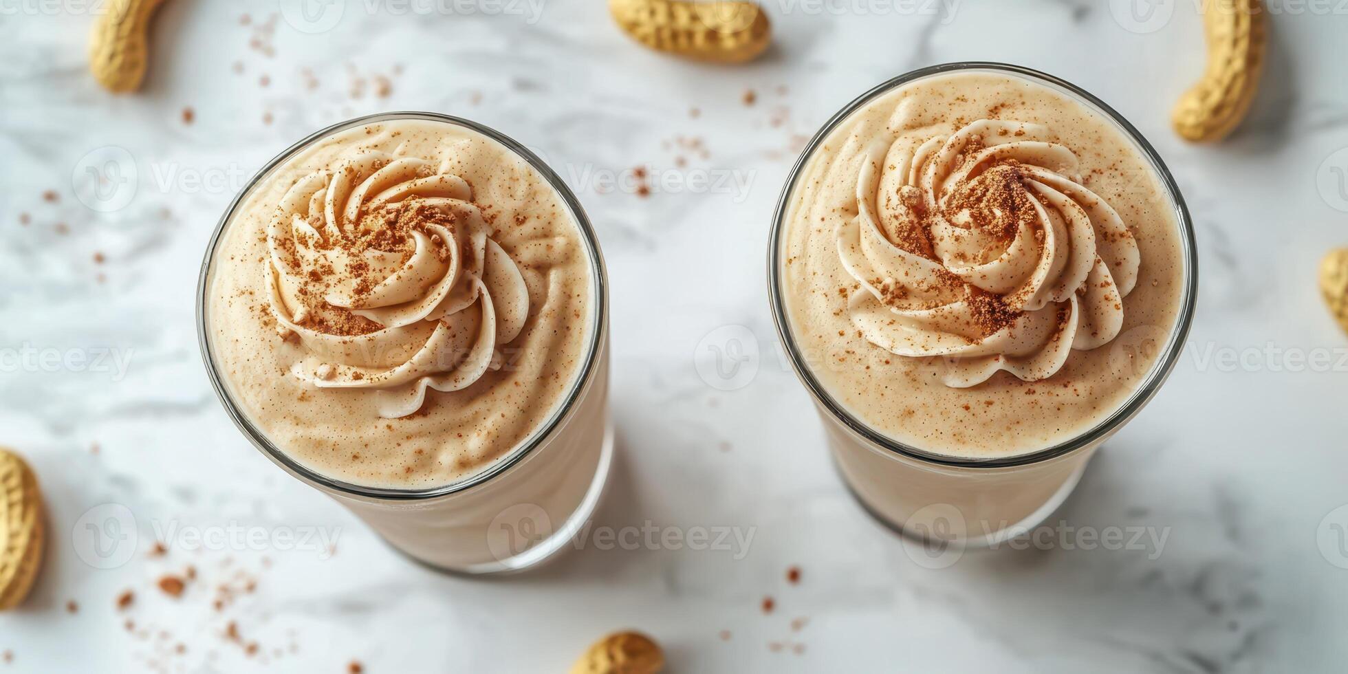 Creamy peanut butter smoothies topped with whipped cream and sprinkled with cinnamon on a marble countertop photo
