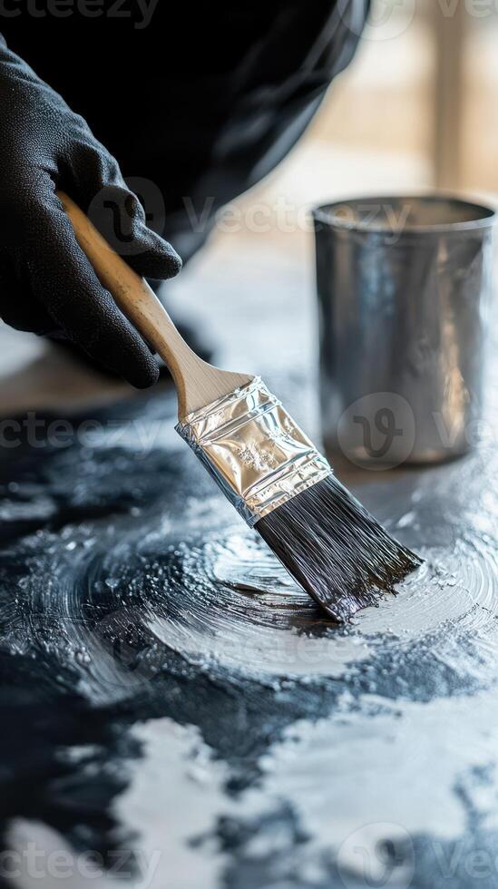 Person painting a surface with a brush and a metal container nearby during a creative indoor project photo