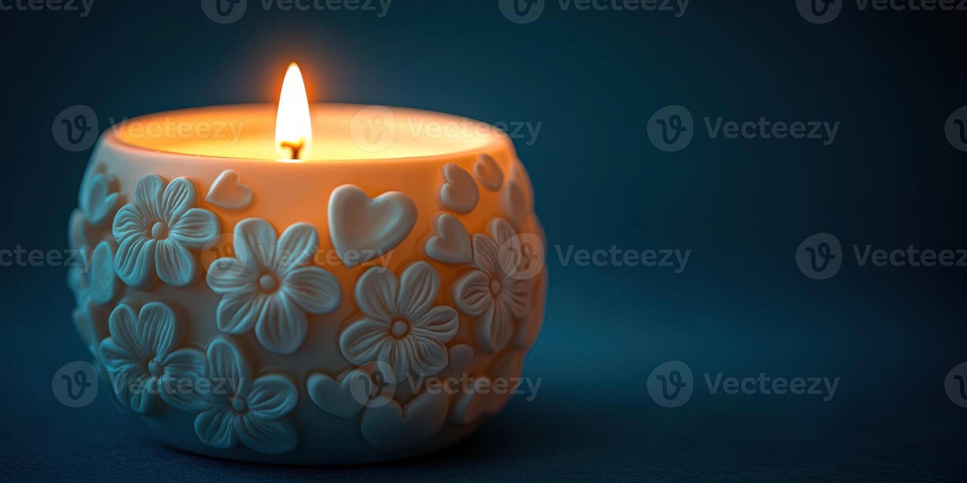 Decorative candle with floral and heart design illuminating a dark background photo