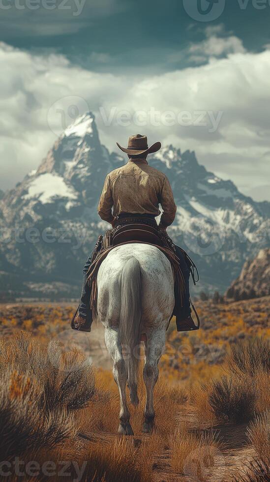 Cowboy riding a white horse through a rugged landscape with mountains in the distance on a cloudy day photo