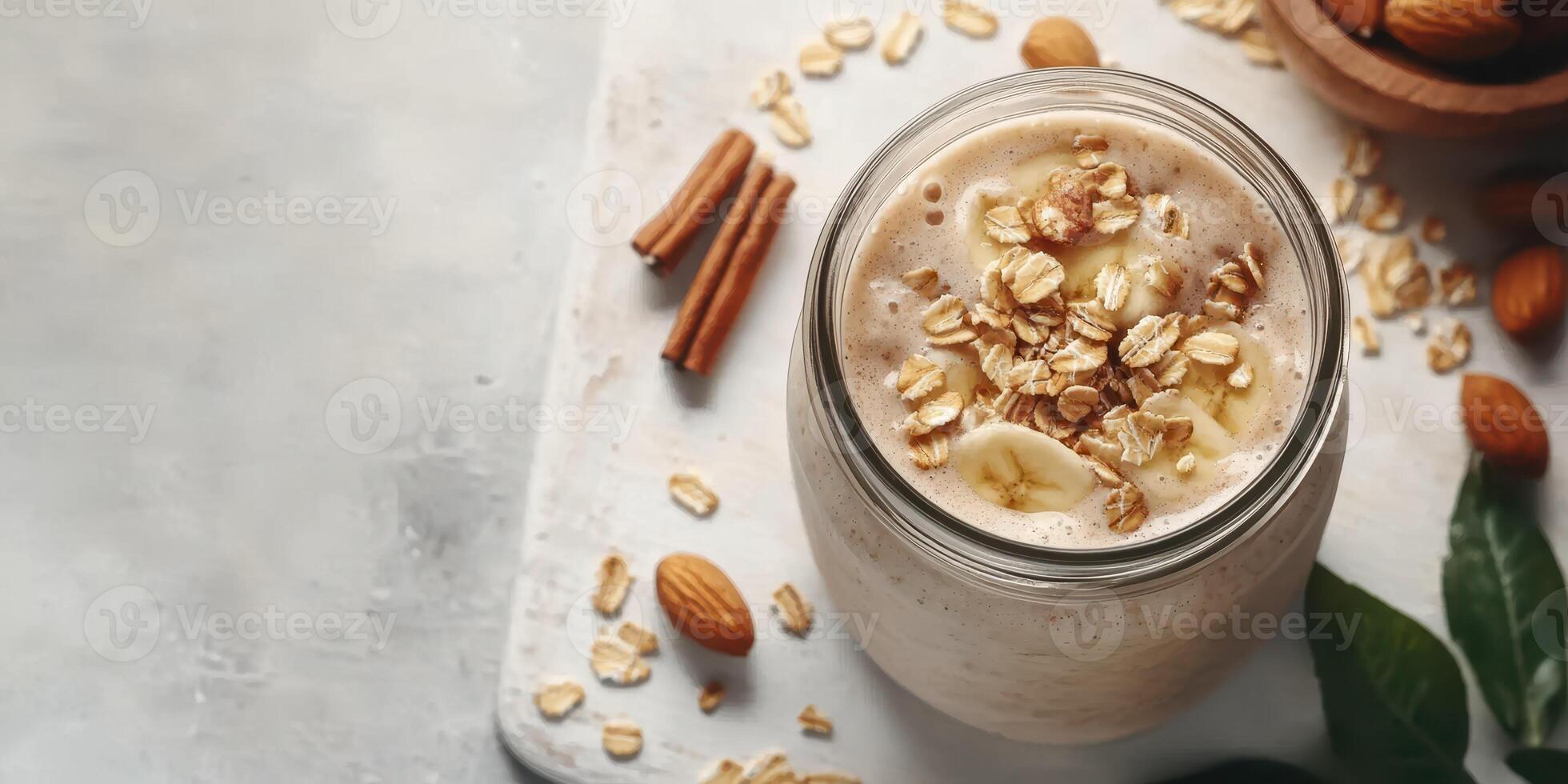 Smoothie with bananas, oats, almonds, and cinnamon on a wooden surface garnished with nuts and leaves photo