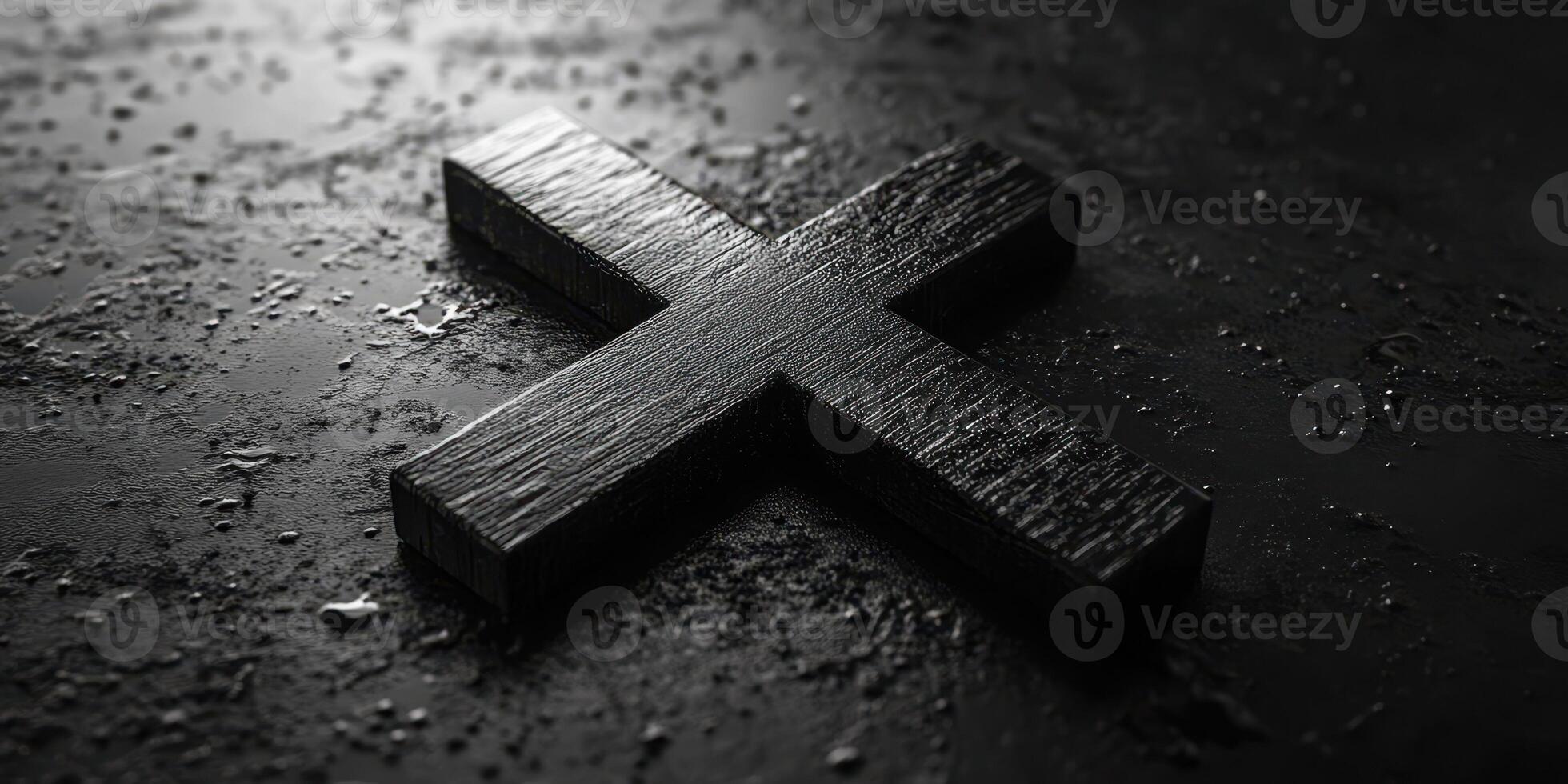 Black wooden cross lies on a textured surface with water droplets reflecting light in a dimly lit setting photo