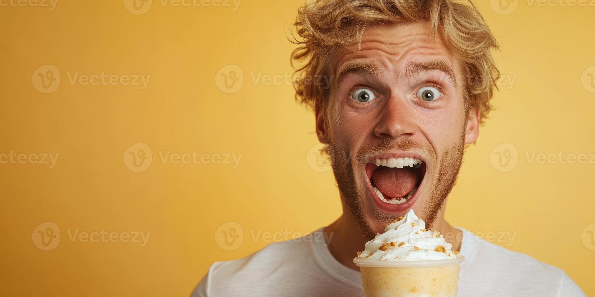 Man joyfully enjoying a dessert beverage with whipped cream against a bright yellow background photo