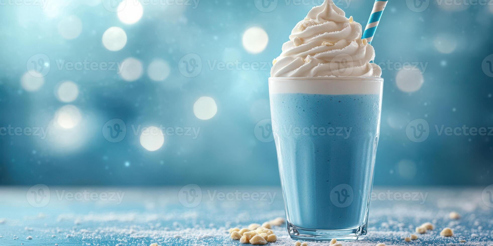 Refreshing blue milkshake topped with creamy whipped cream and a striped straw served in a glass on a sparkling blue background photo
