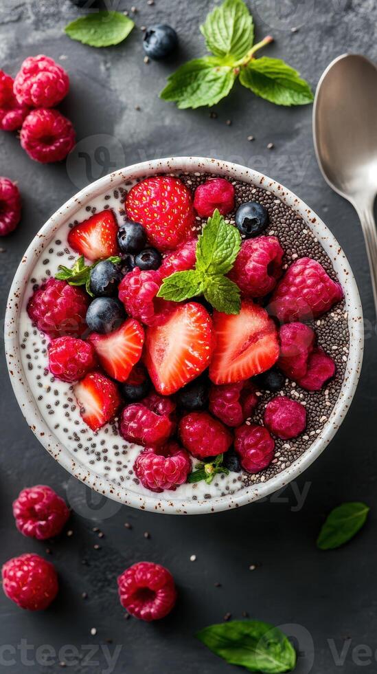 Fresh berry bowl with yogurt and mint served on a dark stone table for a healthy breakfast or snack photo