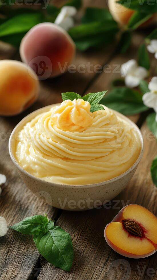 Creamy peach dessert served in a bowl surrounded by fresh peaches and mint leaves on a wooden table photo