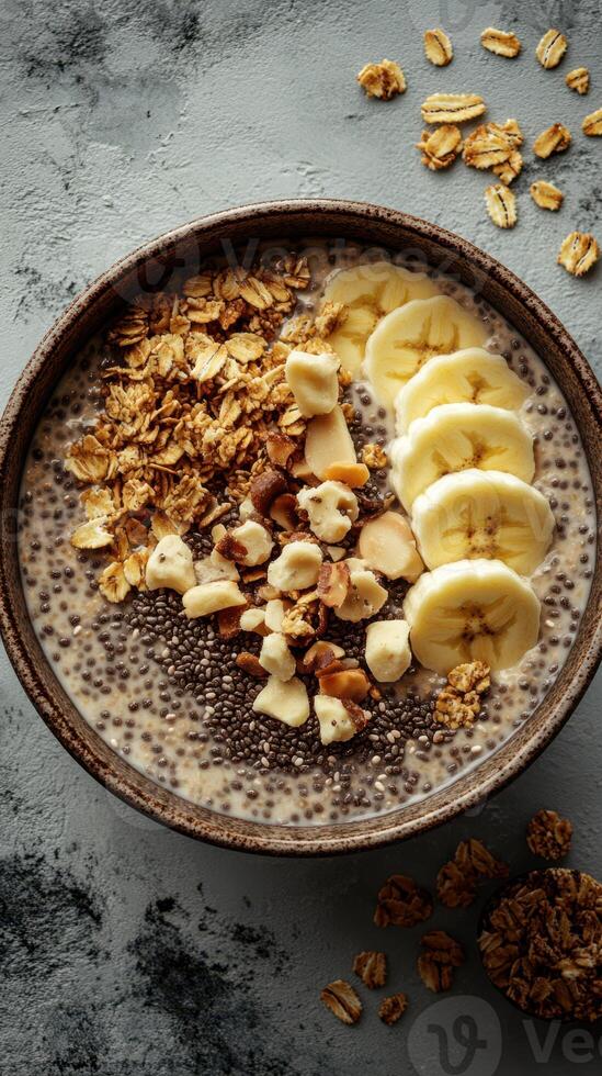 Healthy chia seed pudding topped with banana slices and granola on a textured grey background photo