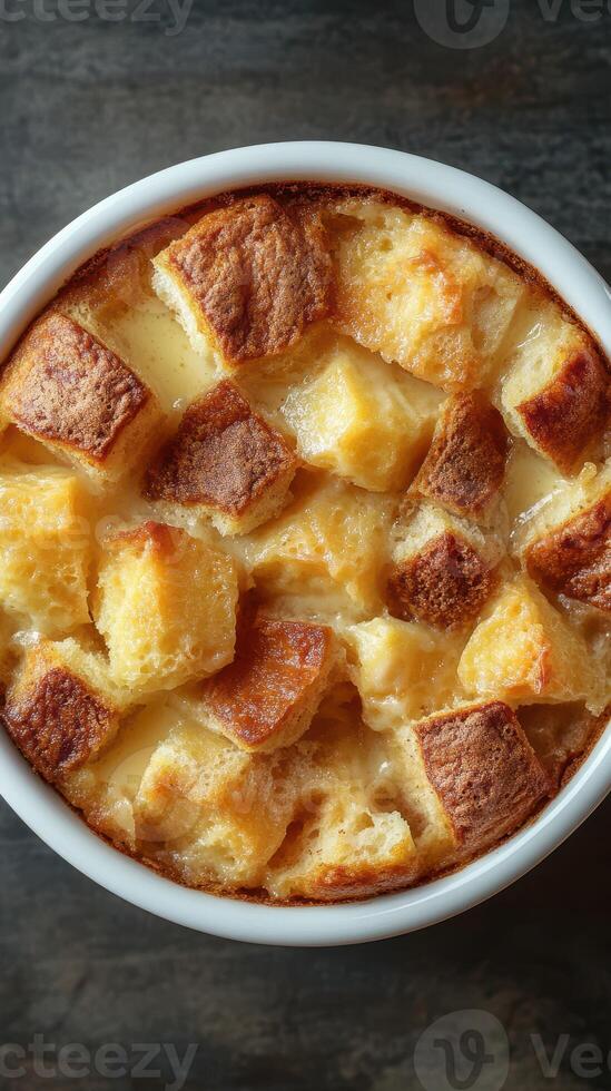 Delicious bread pudding served in a white bowl on a dark background, showcasing golden crust and soft texture photo