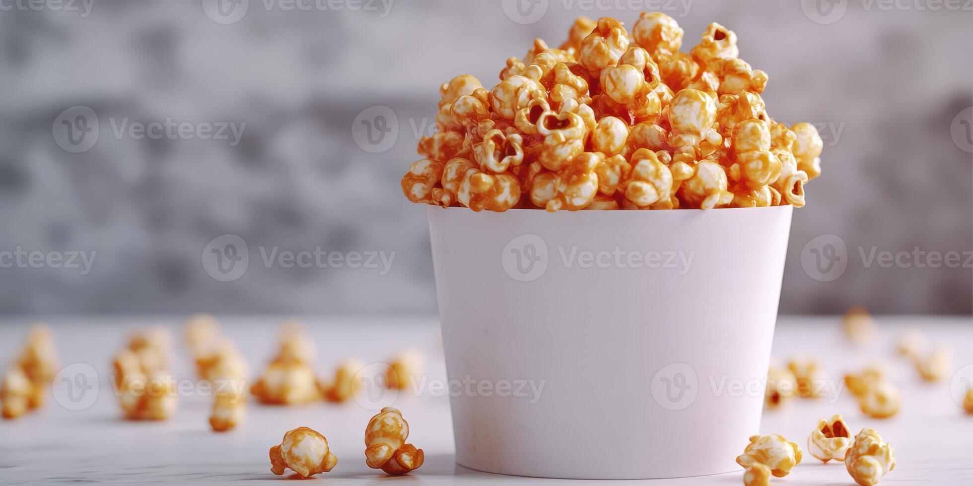 Freshly popped caramel popcorn served in a white cup with scattered pieces on a marble surface photo