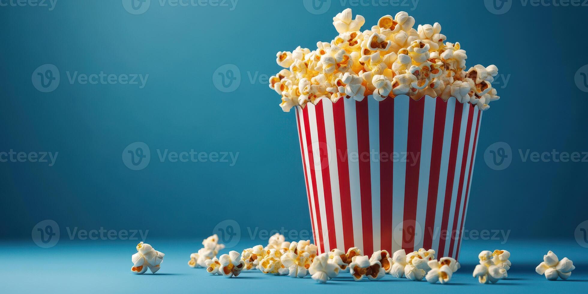 Deliciously fresh popcorn in a striped bucket on a vibrant blue background at a cinema or movie night setting photo
