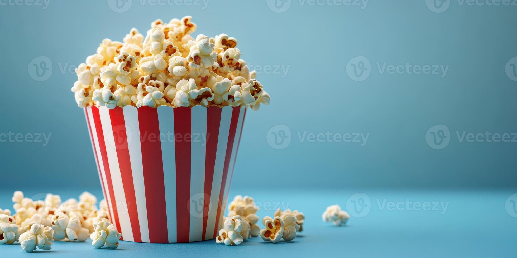 Delicious popcorn served in a striped container on a blue background perfect for movie night or snack time photo