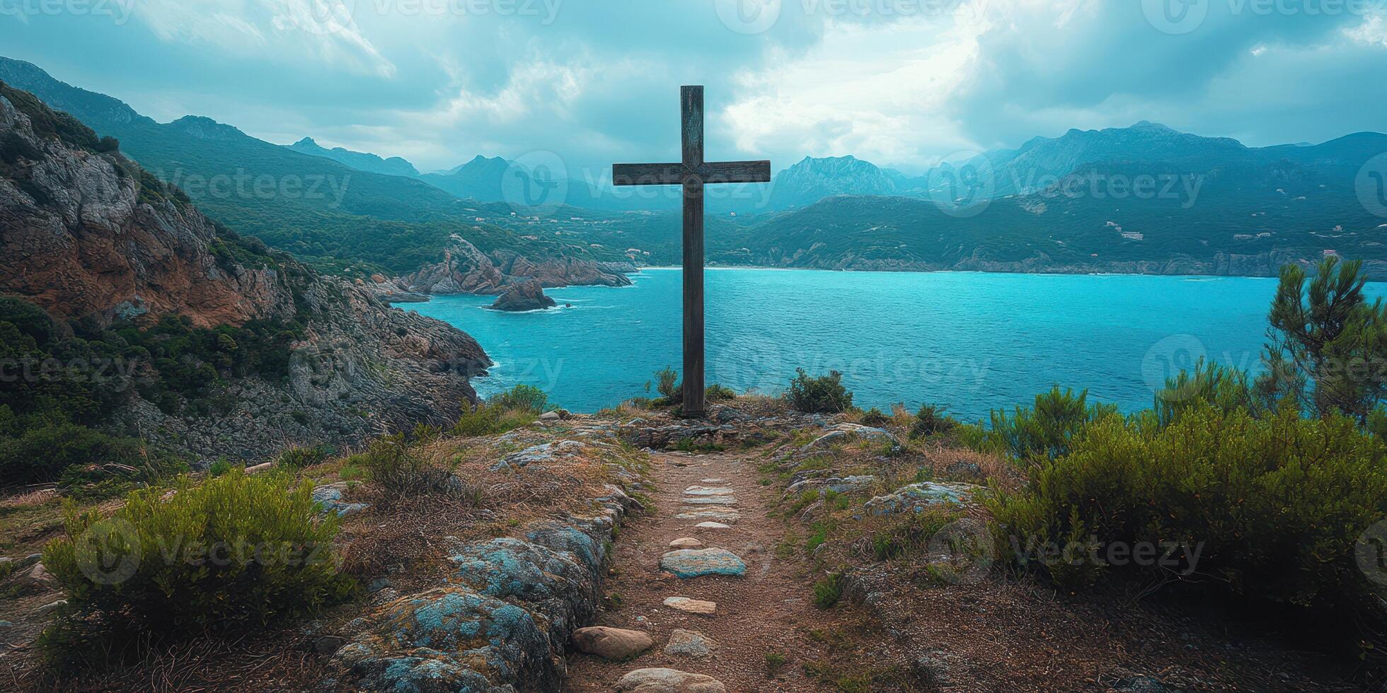 Cross overlooking a stunning coastal landscape with turquoise waters and dramatic mountains in the background photo