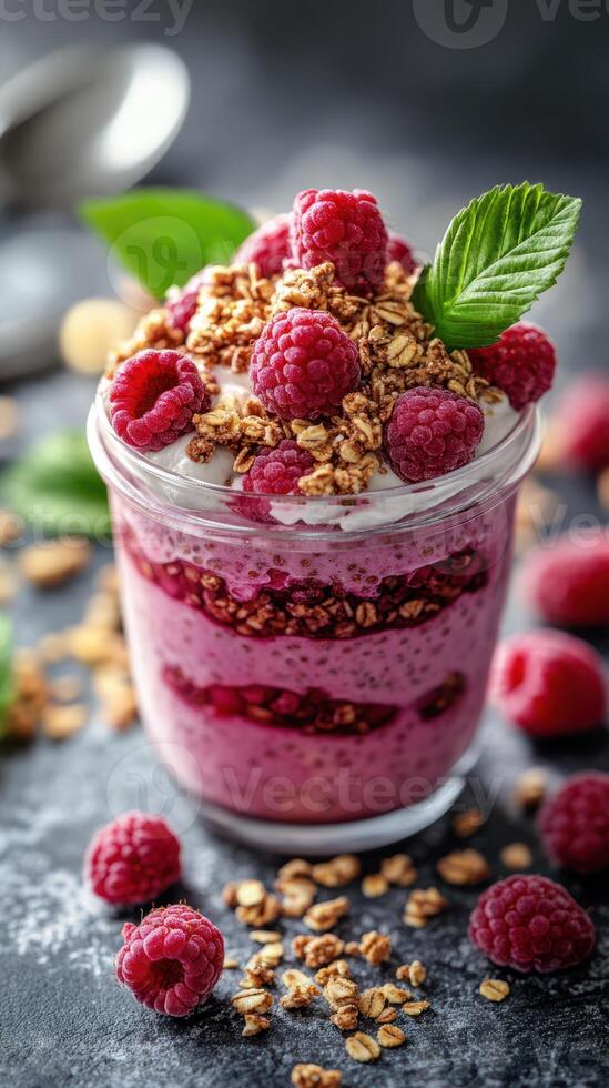 Vibrant raspberry parfait with granola in a glass jar on a textured surface photo