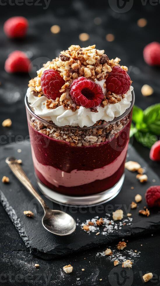 Delicious layered dessert featuring raspberries and crushed nuts served in a glass with whipped cream photo