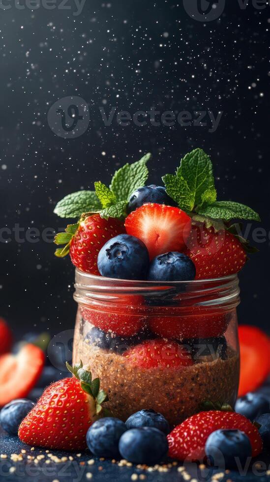 Fresh berries layered in a glass jar with mint leaves and a dark background create a vibrant dessert display photo