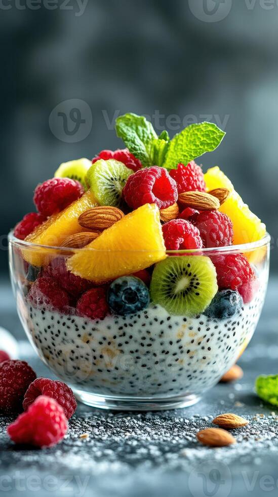 Colorful fruit salad with chia seeds, nuts, and fresh mint garnish presented in a clear bowl photo