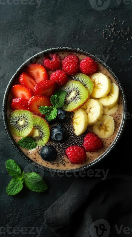 Colorful fruit bowl with sliced strawberries, bananas, and kiwis arranged on a dark background photo