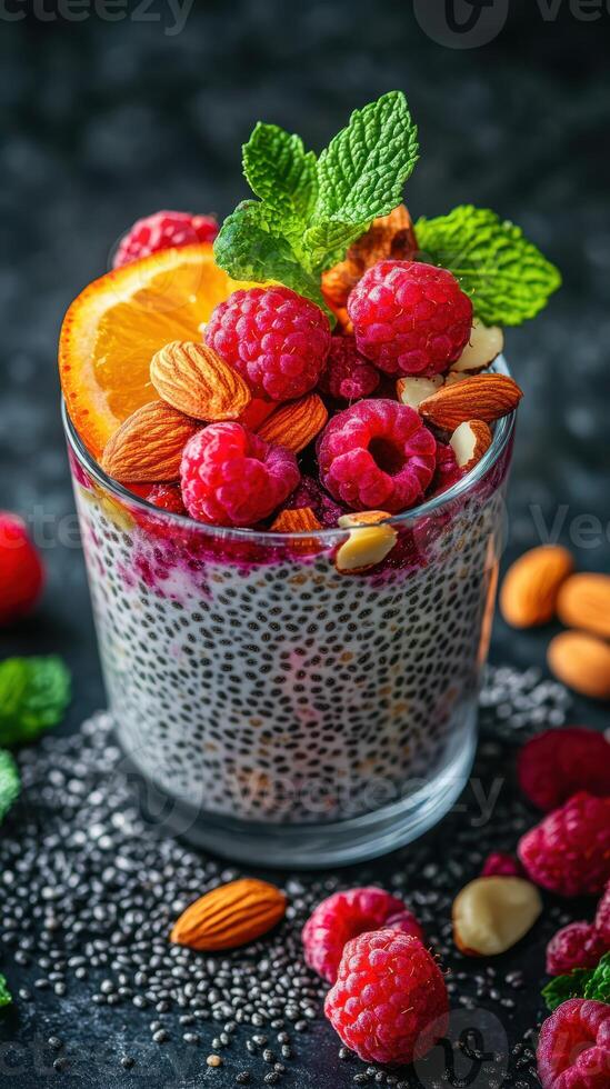 Chia pudding topped with fresh raspberries, oranges, and almonds captured on a black stone surface photo