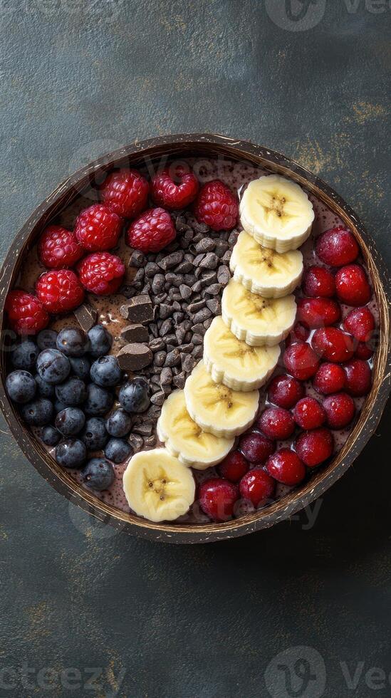 Colorful dessert bowl featuring fresh fruits and chocolate in an artistic arrangement on a textured background photo