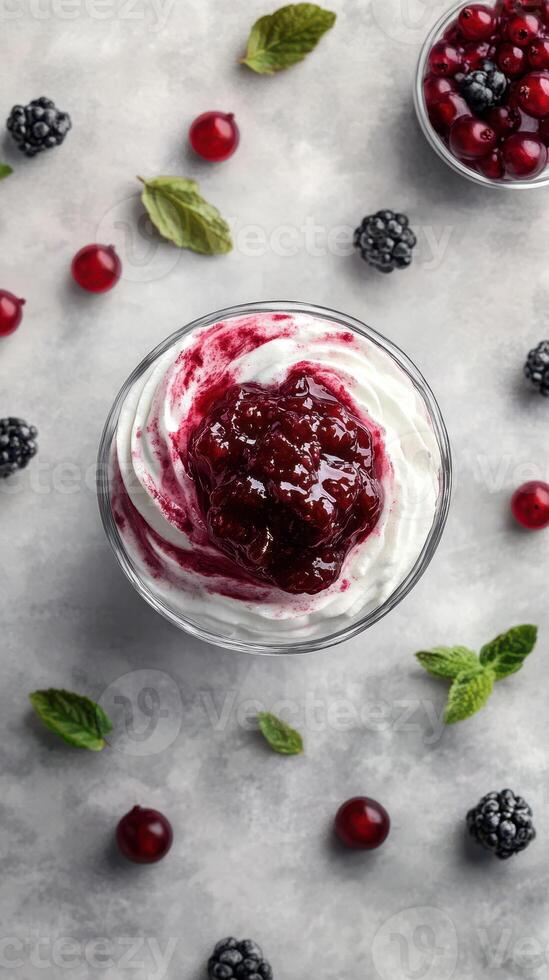 Delicious dessert topped with berry compote surrounded by fresh fruits and mint leaves photo