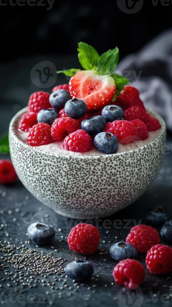 Fresh berries with chia seeds in a textured bowl on a dark surface with mint garnish and scattered fruit photo