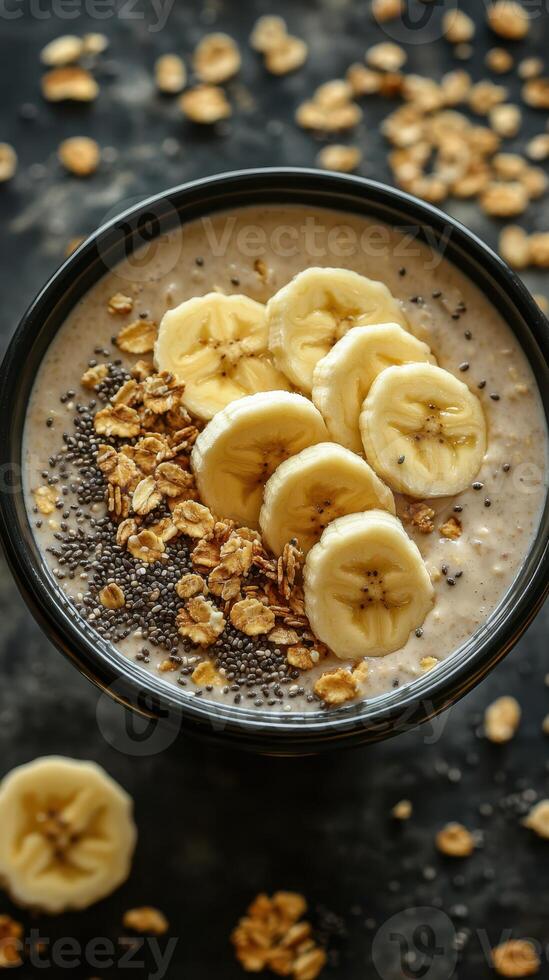 Healthy breakfast bowl with banana slices, chia seeds, and oats served in a black bowl on a dark surface photo