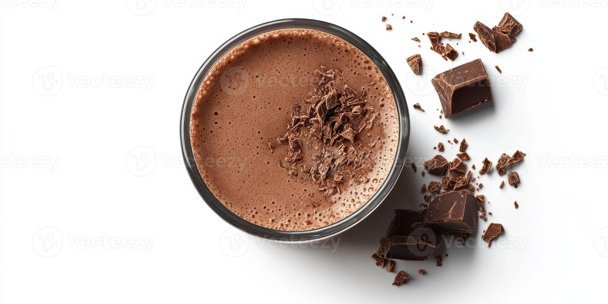 Rich hot chocolate topped with chocolate shavings placed next to chocolate chunks on a white background photo