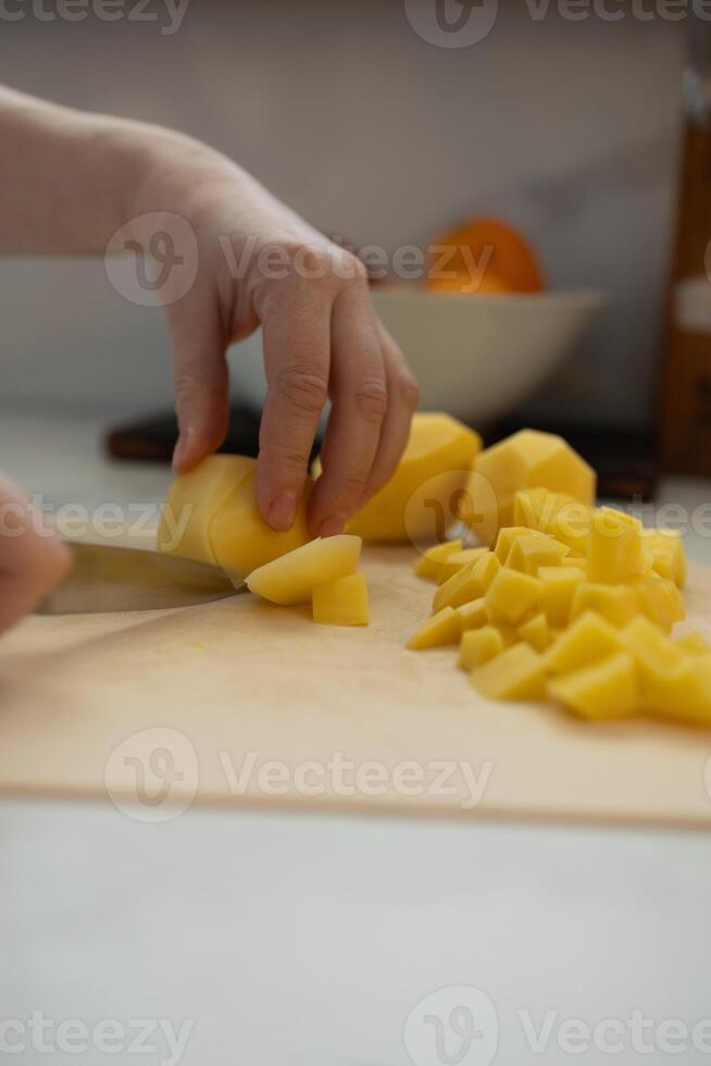 Carefully chop fresh potatoes in a bright and modern kitchen today photo