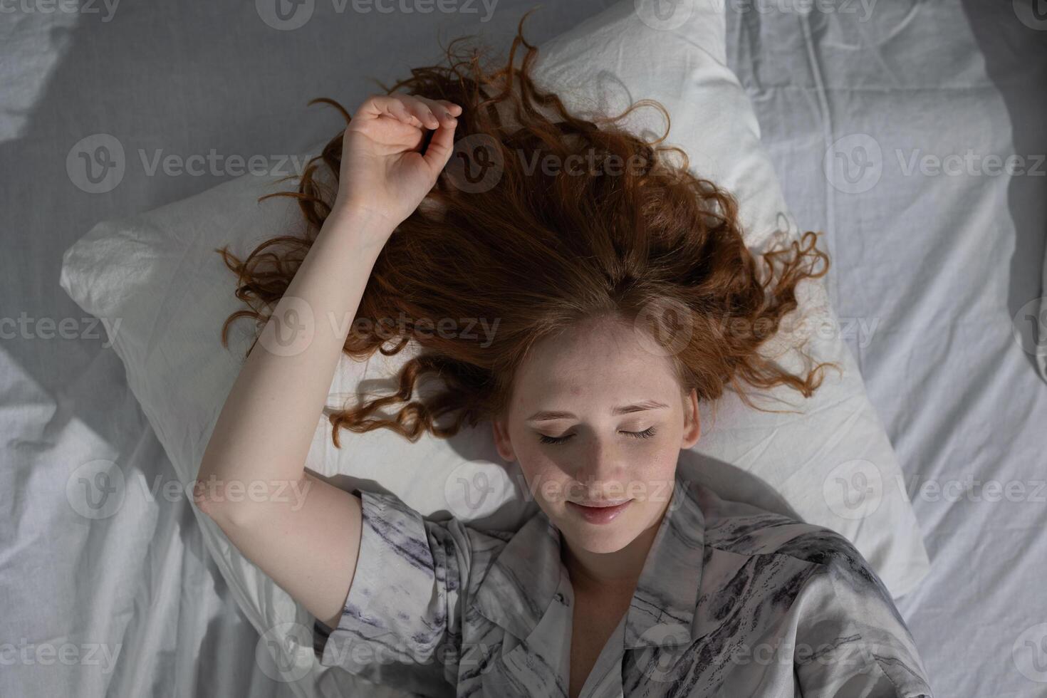 A woman is comfortably laying in bed with her head resting on a soft pillow photo
