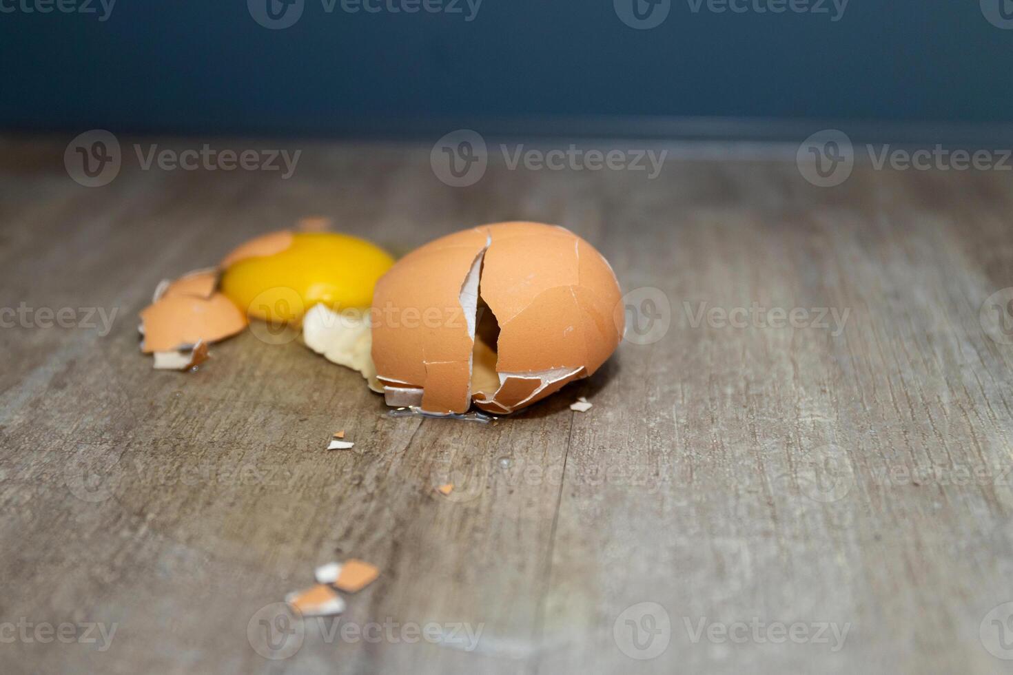 A Cracked Egg Shell Presenting the Yolk on a Wooden Surface, Ready for Cooking Delights photo