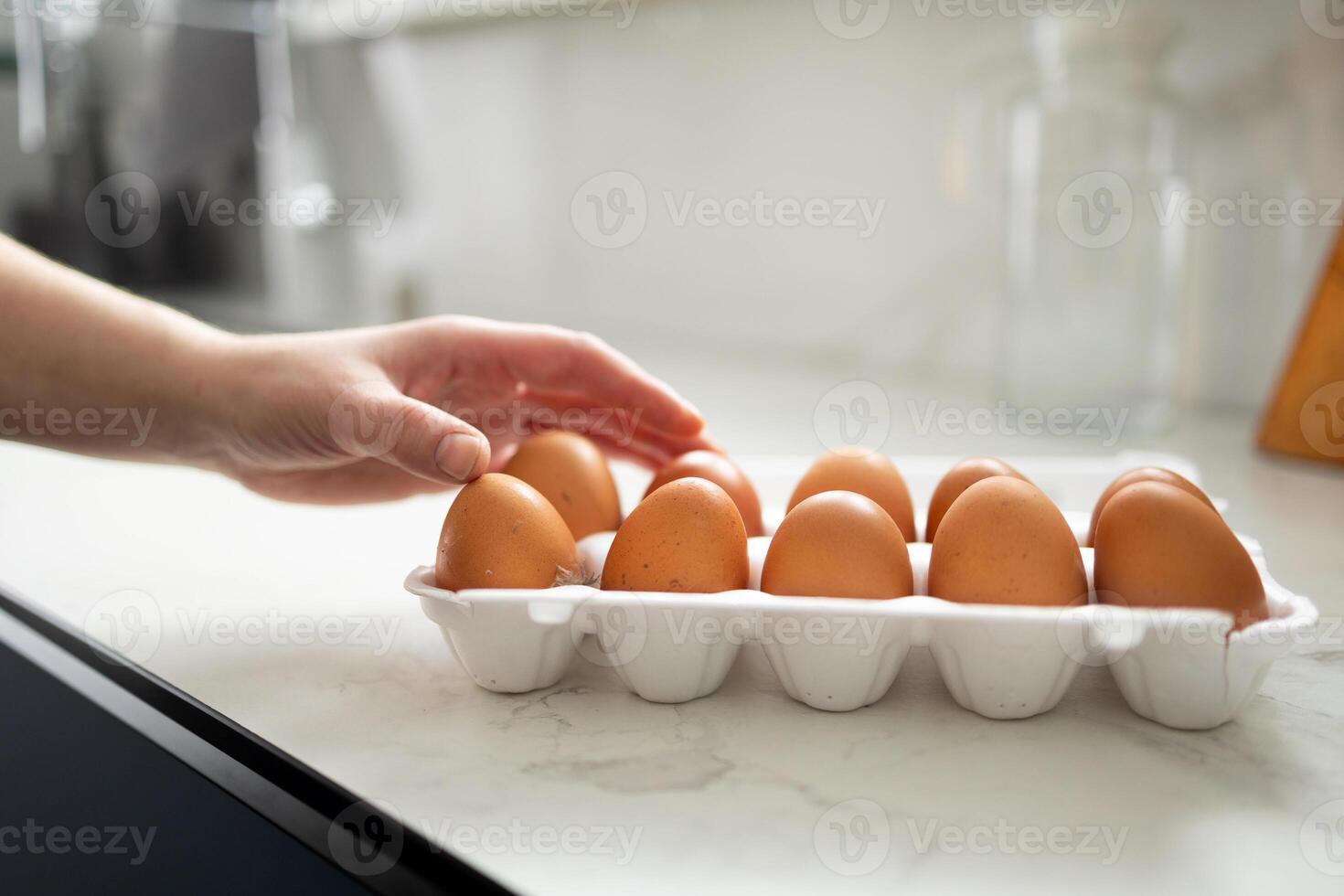 A carton filled with fresh brown eggs is placed on the kitchen counter waiting to be used photo
