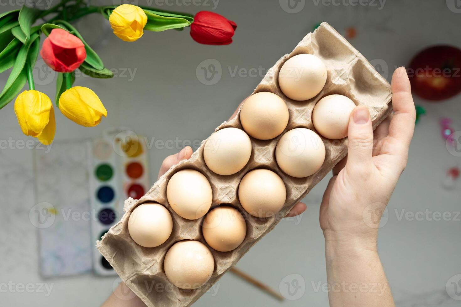 A Carton Filled with Fresh Eggs Gracefully Surrounded by Colorful Tulips and Various Art Supplies photo