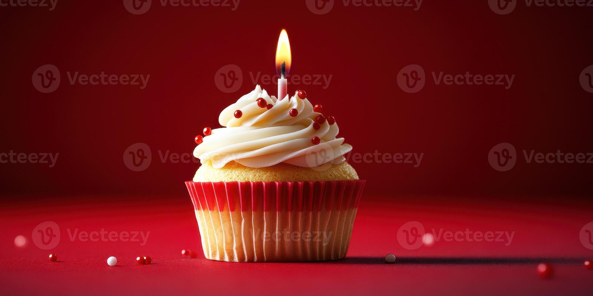 Colorful cupcake with a lit candle on a vibrant red background creates a festive atmosphere for celebration photo